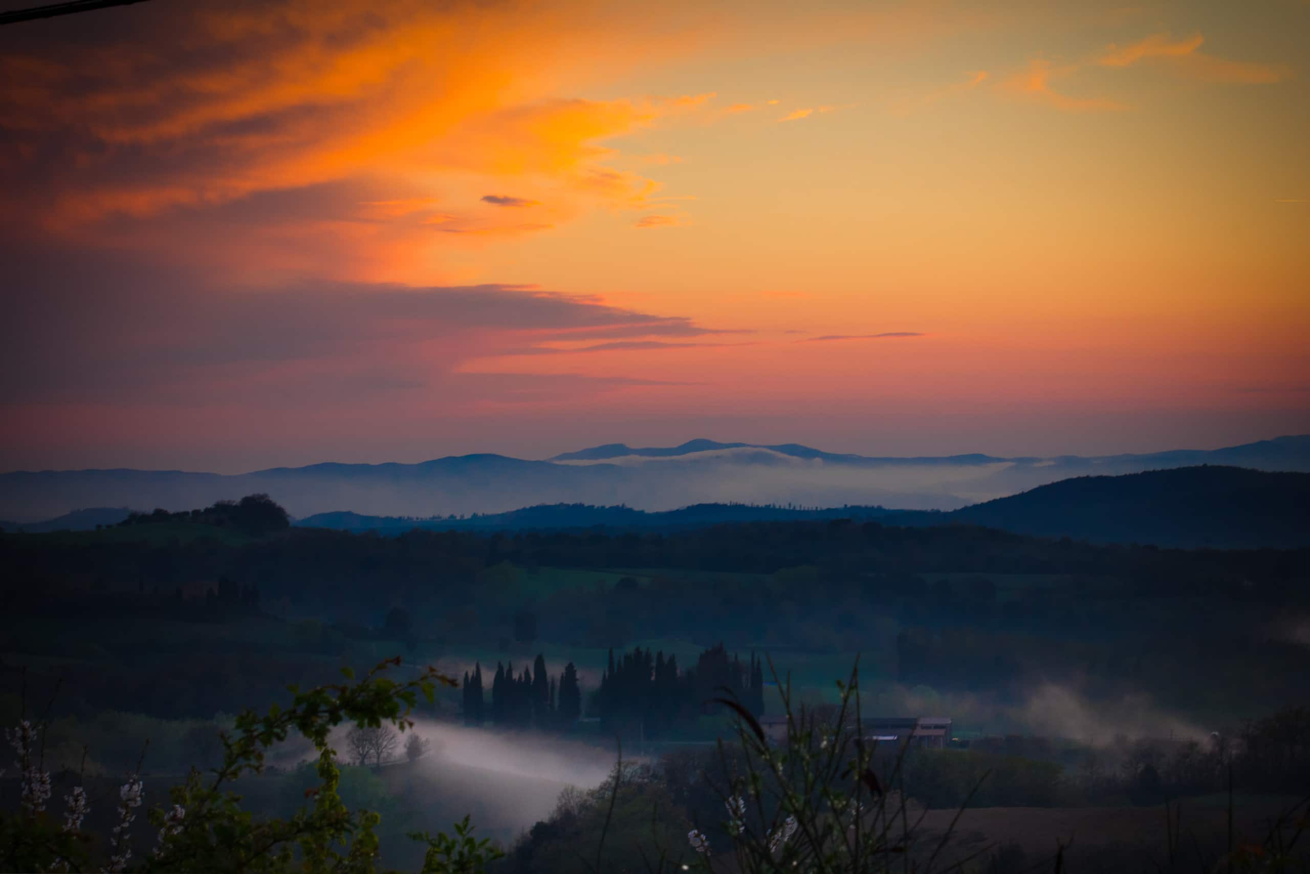 Colline toscane avvolte dalla foschia al tramonto